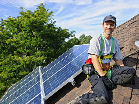 man installing solar panels on roof