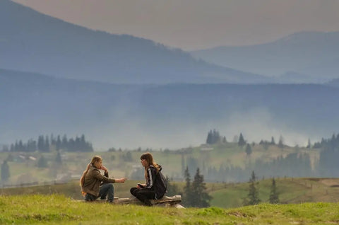 two girls sitting in a field and talking